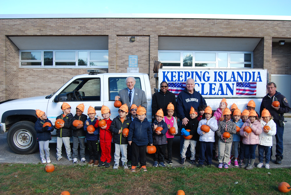 Joining the students at Andrew T. Morrow Elementary School with their pumpkins are (standing, left to right) Dr. Howard Koenig, Superintendent of Schools, Central Islip Union Free School District; Dr. Neema Coker, Principal, Andrew T. Morrow Elementary School; Allan M. Dorman, Mayor, Village of Islandia; and Gerald Peters, Building Inspector, Village of Islandia. The pumpkins were donated by the Village.