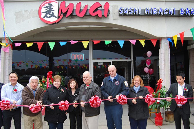 Mayor Allan M. Dorman (third from right), Village of Islandia, prepares to cut the ribbon in celebration of the grand opening of Mugi Sushi Hibachi & Bar with village officials and Mugi's owners and managers on November 16.