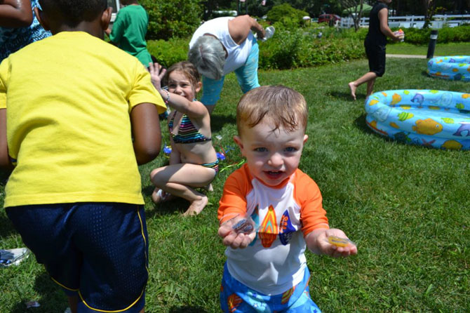 Two-year-old Gavin Schrage shows off the two pieces of candy that he received from the piñata at Islandia Village’s 9th annual BBQ.