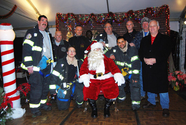 Islandia Village Mayor Allan M. Dorman (front row, right) is joined by Mike Zaleski (back row, second from right), Santa Claus and members of the Central Islip Fire Department during the village’s 8th annual Christmas tree lighting ceremony on December 7.