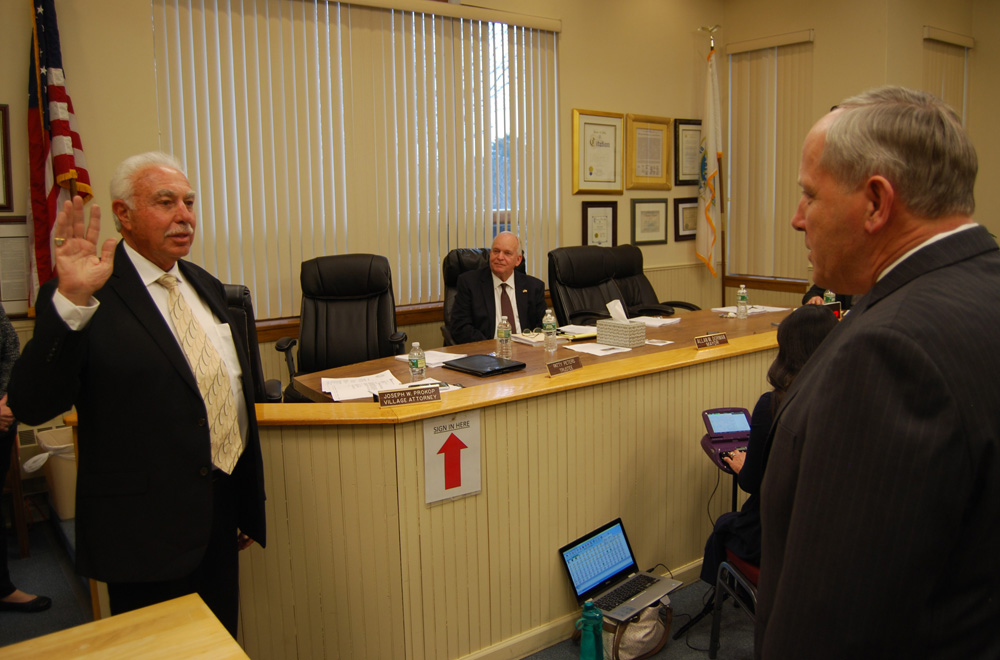 Village Justice Alan Wolinsky is sworn in by Joseph W. Prokop (foreground), Village Attorney, during a special ceremony on April 2 at Village Hall as Mayor Allan M. Dorman (seated) observes.