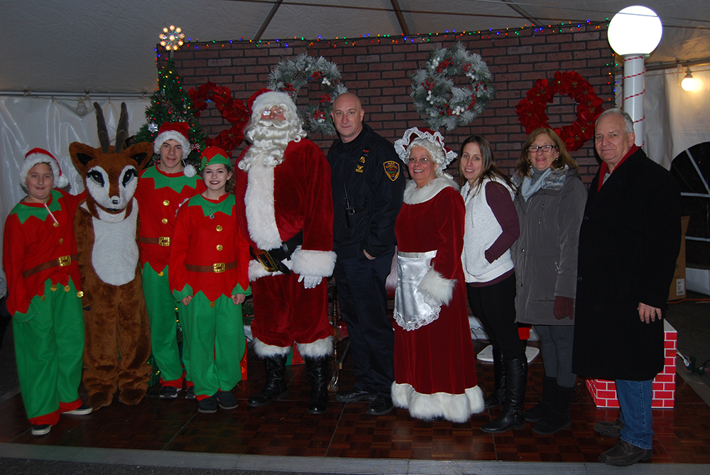 Islandia Village Mayor Allan M. Dorman (right) is joined by Santa Claus (fifth from left), Rudolph the Red-Nosed Reindeer (second from left), Santa’s elves and village officials at the eleventh annual Christmas tree lighting ceremony on December 10. Also pictured: Michael Zaleski (fifth from right), Deputy Mayor; “Mrs. Claus” Barbara Lacey (fourth from right), Trustee; Denise Schrage (third from right), Village Activities Director; and Patty Peters (second from right), Trustee.