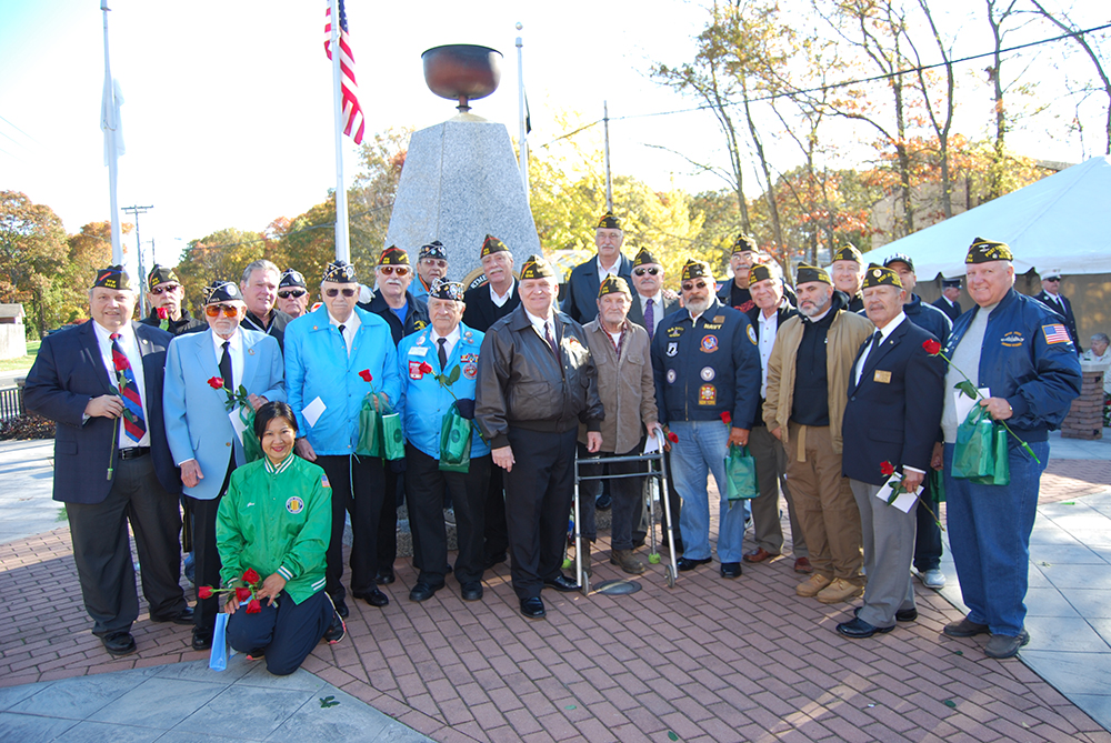 Mayor Allan M. Dorman (front row, center) poses with the members of the Col. Francis S. Midura Veterans of Foreign Wars Post #12144, the Central Long Island Chapter of the Korean War Veterans Association and other war veterans at the Village of Islandia’s Veterans Day ceremony on November 5. He is also joined by New York State Assemblyman Al Graf (back row, third from left) and Gina Lekstutis (kneeling), Owner, Gina’s Flower Shoppe.