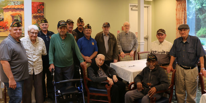 Allan M. Dorman (standing, front row, left), Mayor, Village of Islandia, and Raul Jimenez Cintron (standing, front row, fourth from left), Commander, Col. Francis S. Midura Veterans of Foreign Wars Post #12144, are joined by local war veterans and members of VFW Post #12144 at the Arbors Assisted Living at Islandia West during the “Vets’ Chat” on July 24.