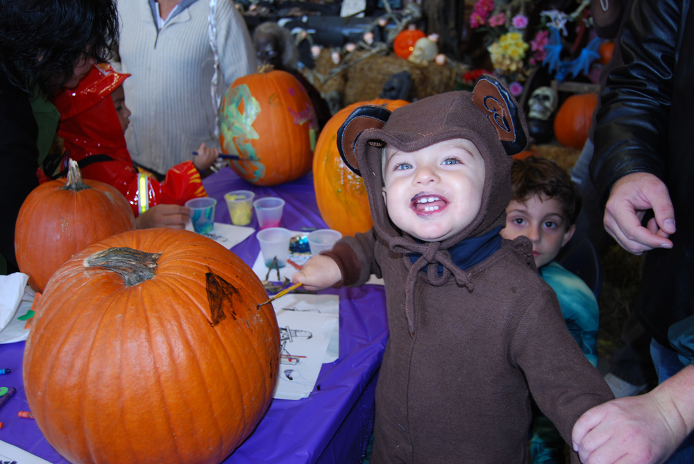 18-month-old Vito Sacino, son of Vito and Krista Sacino of Islandia, is dressed up in costume and touched up with some paint from kissing the pumpkin he just painted at Islandia Village’s Fourth Annual Craft Fair and Pumpkin Fest.