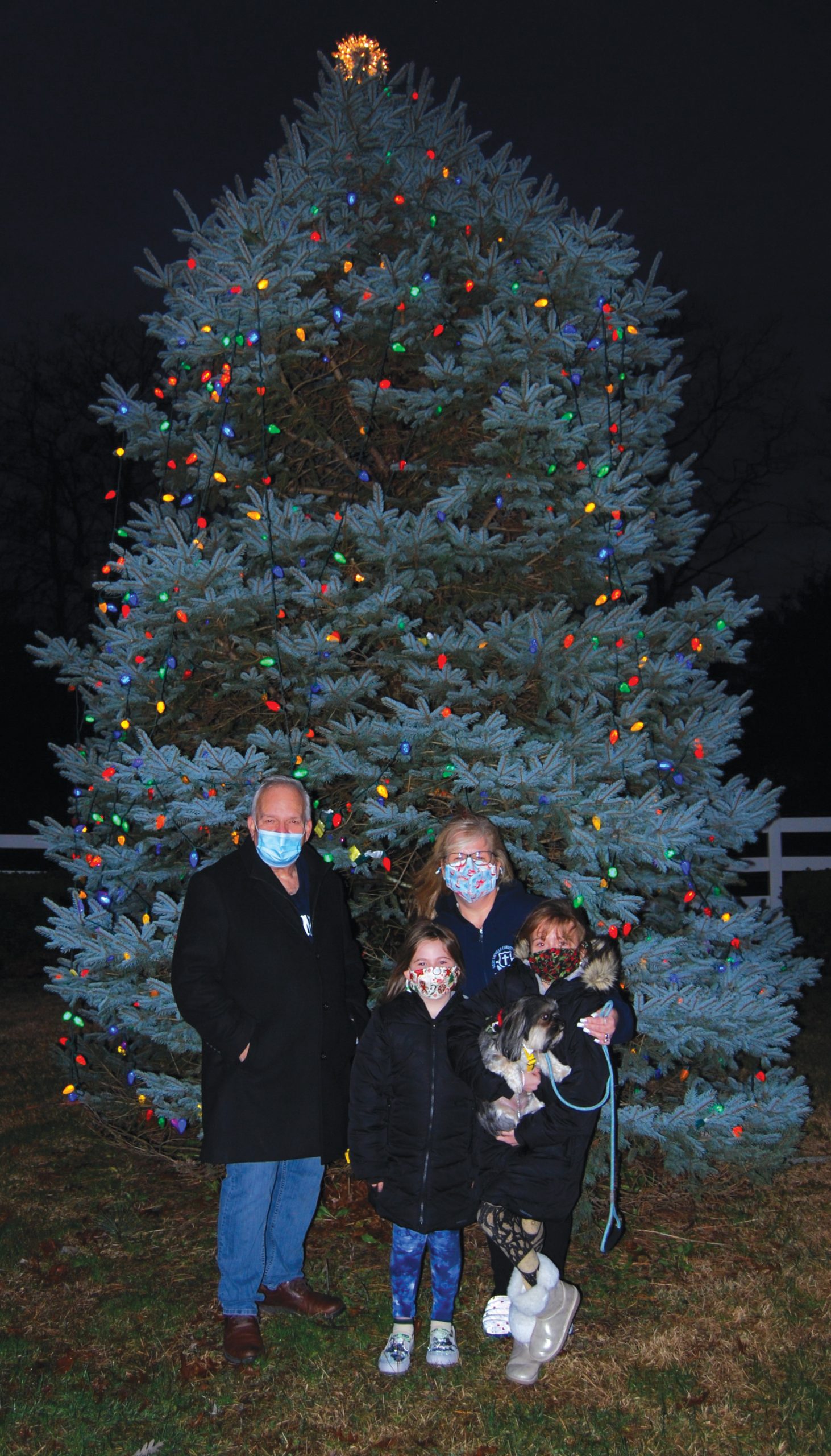 Mayor Dorman (left) poses in front of the Christmas tree with Donna Delvalle, her granddaughters Donnabella Delvalle and Madison Delvalle and their dog Toby during the village’s drive-through Christmas tree lighting.